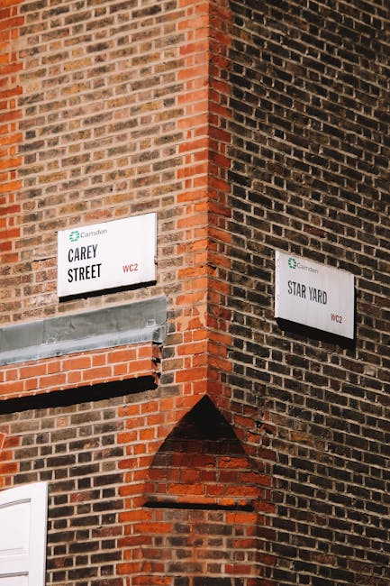 The image depicts the entrance to Camden Market, with a prominent arched sign that reads 'CAMDEN MARKET' positioned above the street. The scene is set during daytime with partly cloudy skies visible a